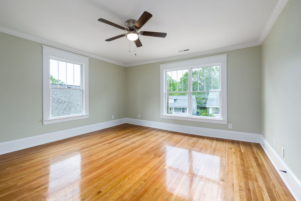 An empty room with a newly recoated oak floor reflecting the window light.